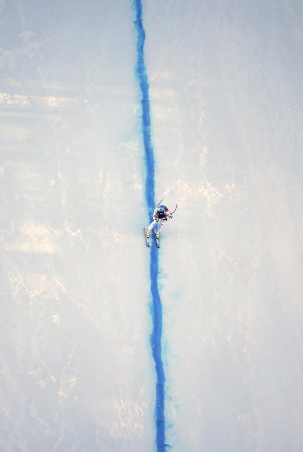 Eine Skifahrerin fährt eine blaue Linie im Schnee hinunter.