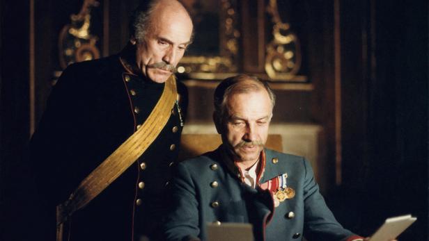 Zwei Männer in Uniformen, vermutlich aus einem historischen Film, betrachten ein Dokument.
