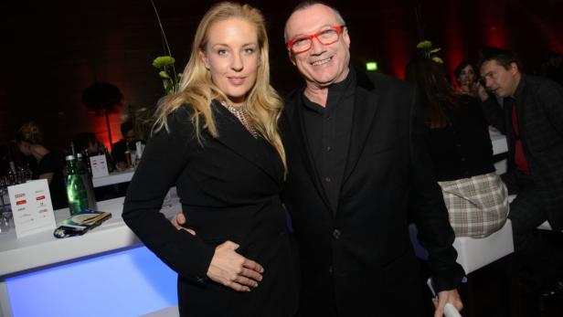 Eine blonde Frau und ein Mann mit roter Brille posieren für ein Foto.