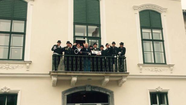 Eine Gruppe von Menschen steht auf einem Balkon und winkt.