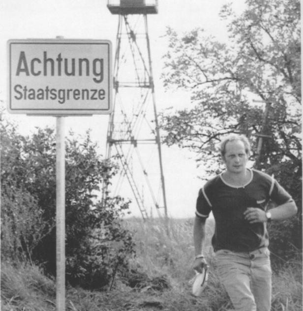 Ein Mann geht an einem Schild mit der Aufschrift „Achtung Staatsgrenze“ vorbei.