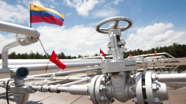 Eine Ölraffinerie mit einer venezolanischen Flagge im Hintergrund.