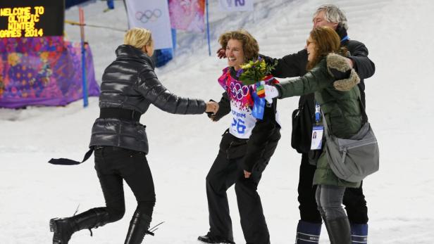 Ein Snowboarder wird nach einem Wettbewerb von Freunden und Familie umarmt.