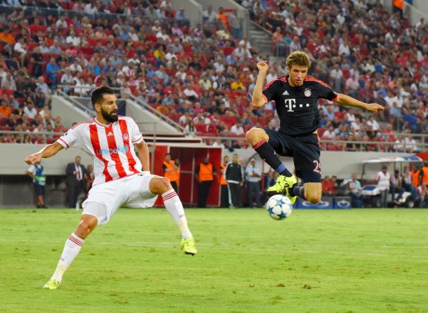Zwei Fußballspieler kämpfen vor einer Zuschauermenge um den Ball.