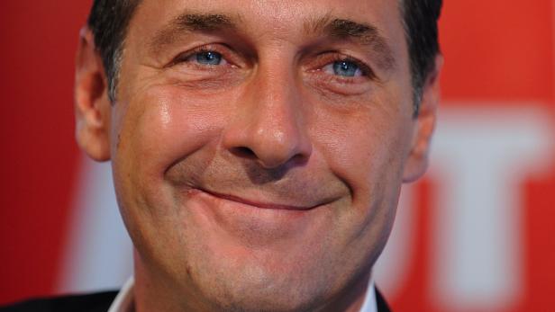 Nahaufnahme eines lächelnden Mannes mit blauen Augen vor einem roten Hintergrund.
