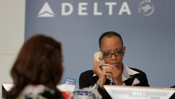 A Delta Airlines ticketing agent assists a passeng Nach Computerpanne 451 Flüge gestrichen