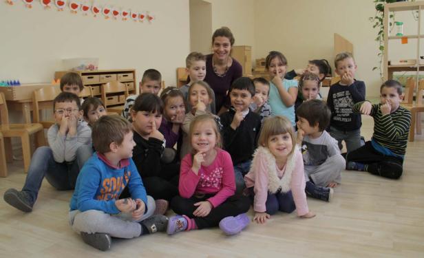 Eine Gruppe von Kindern sitzt mit einer Erzieherin in einem Raum.