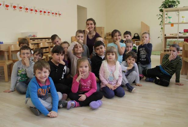 Eine Gruppe von Kindern sitzt mit einer Erzieherin in einem Raum.