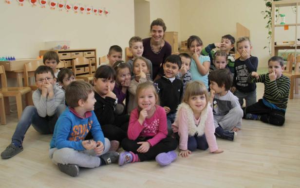 Eine Gruppe von Kindern sitzt mit einer Erzieherin in einem Raum.