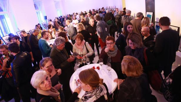 Eine große Gruppe von Menschen versammelt sich in einer Kunstgalerie.