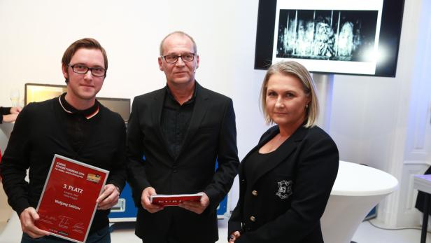 Drei Personen posieren mit Urkunden für einen Fotowettbewerb.