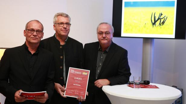 Drei Männer posieren mit einer Urkunde für den 3. Platz eines Fotowettbewerbs.