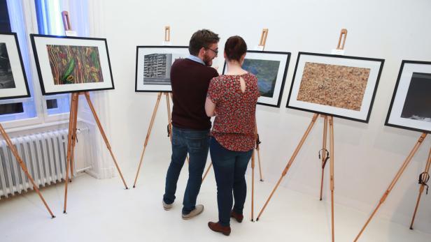 Ein Mann und eine Frau betrachten Fotografien in einer Kunstgalerie.