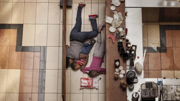 Eine Mutter und ihre Kinder liegen auf dem Boden eines Geschäfts.