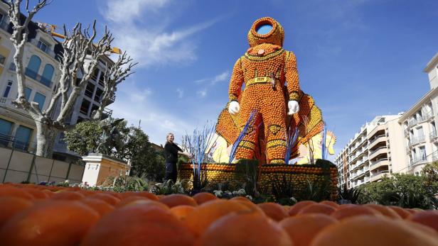 Eine Frau steht neben einer großen Skulptur eines Astronauten, die aus Orangen gefertigt ist.
