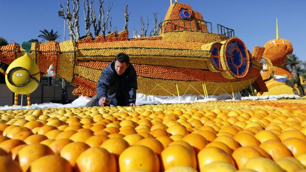 Ein Mann betrachtet eine Skulptur aus Zitrusfrüchten, die ein U-Boot und andere Figuren darstellt.
