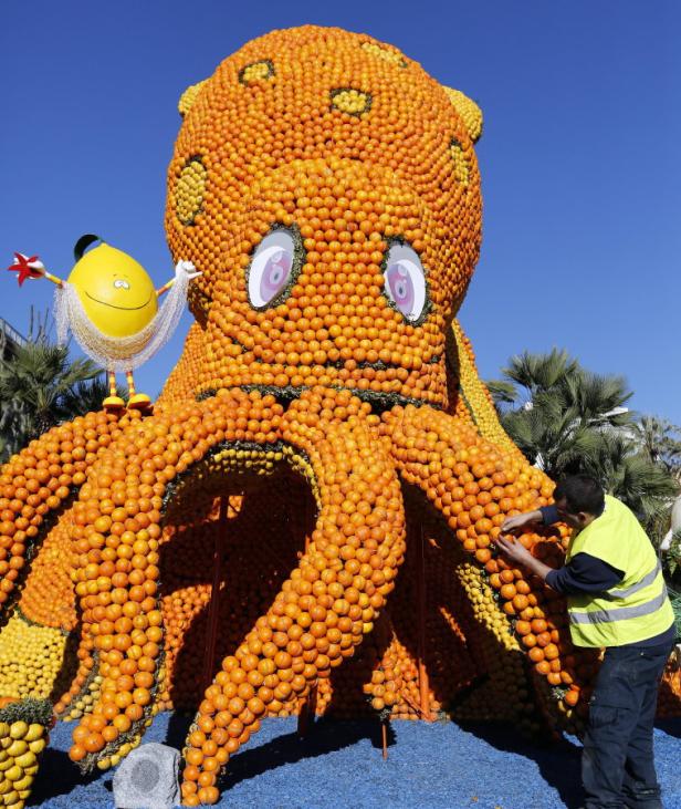 Ein Mann arbeitet an einer großen Skulptur eines Oktopus, die aus Orangen und Zitronen besteht.