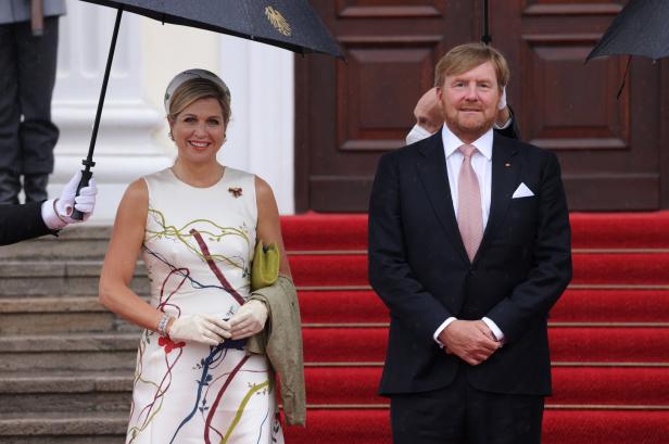 König Willem-Alexander und Königin Máxima der Niederlande stehen unter einem Regenschirm.