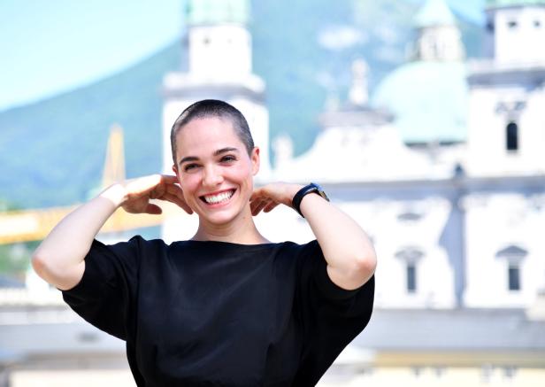 Eine lächelnde Frau posiert vor der Salzburger Festung Hohensalzburg.