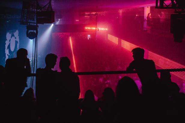 Menschenmenge in einem Nachtclub mit roter und blauer Beleuchtung.