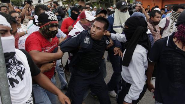 Protesters apprehend a riot police officer during