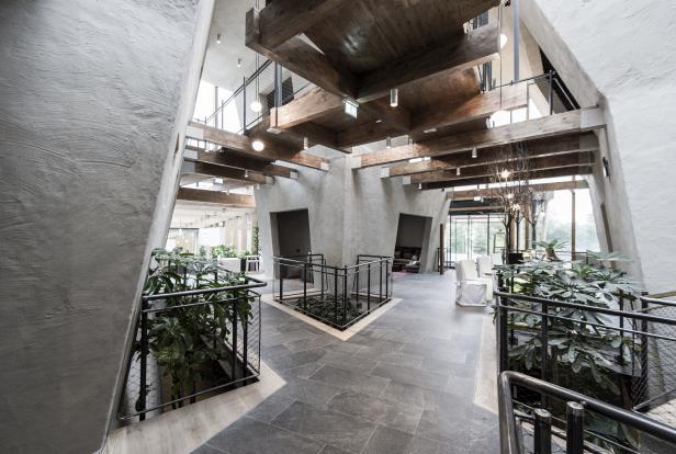 Ein Innenraum mit grauen Steinböden, Pflanzen und einer Holzdecke.