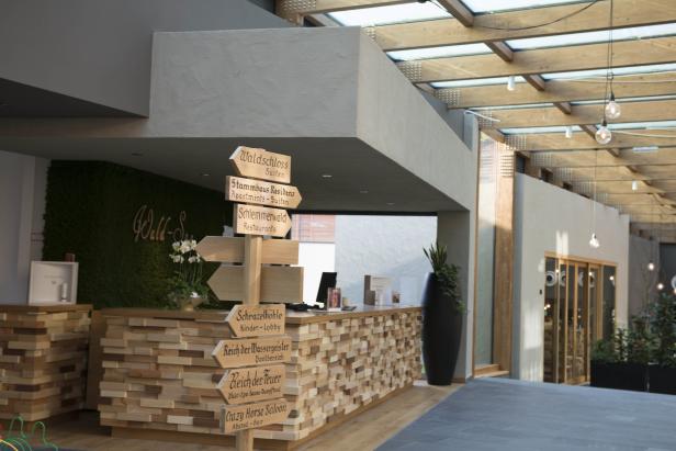 Ein hölzerner Wegweiser zeigt verschiedene Einrichtungen in einem Hotel.