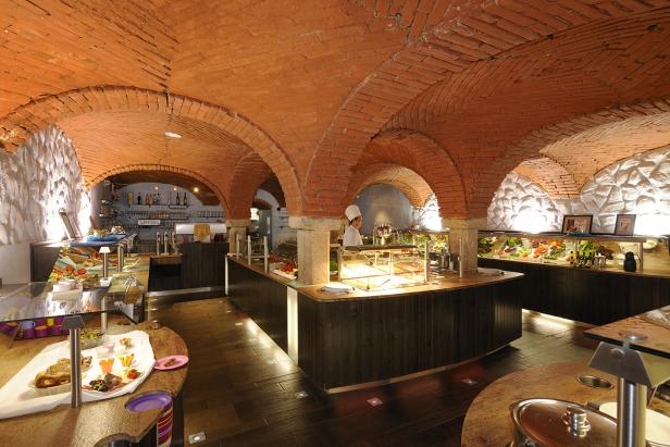 Ein Restaurant mit einem Buffet unter einer gewölbten Ziegeldecke.