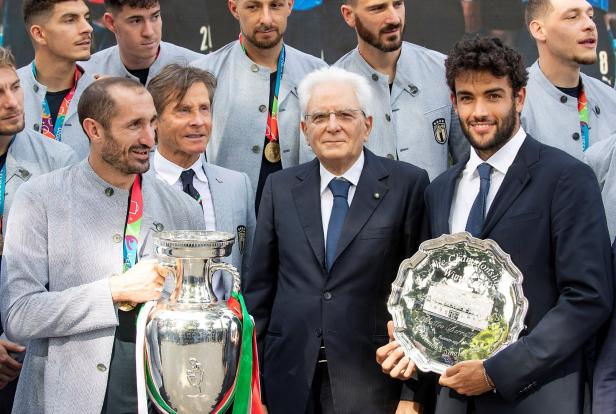Sergio Mattarella mit italienischen Sportlern, die Trophäen halten.