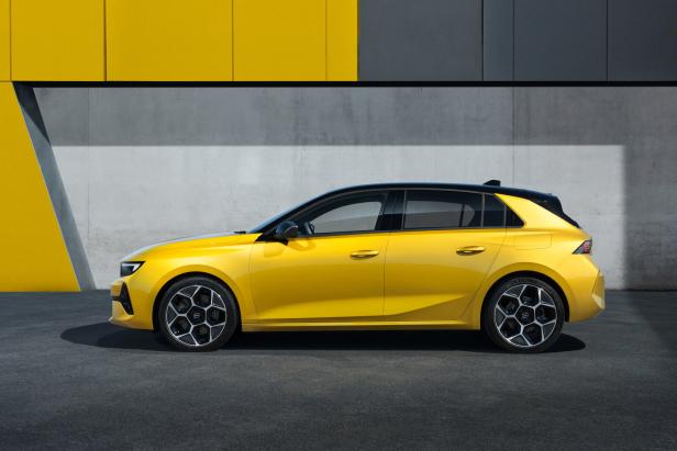 Ein gelber Opel Astra vor einer Wand mit gelben und grauen Elementen.