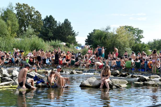 Viele Menschen entspannen sich an einem sonnigen Tag an einem Fluss.
