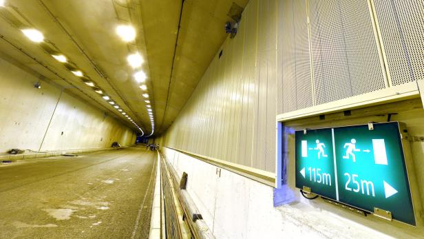 Ein Tunnel mit Notausgangsschildern, die 115 m und 25 m anzeigen.