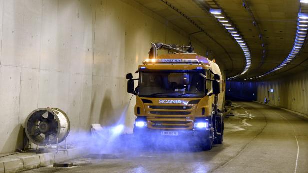 Ein gelber Scania-Lkw reinigt einen Tunnel mit Wasserstrahlern.