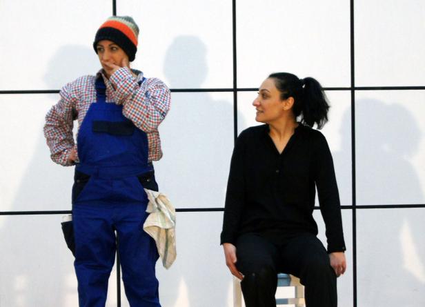 Zwei Frauen stehen vor einer weißen Wand mit schwarzen Linien.