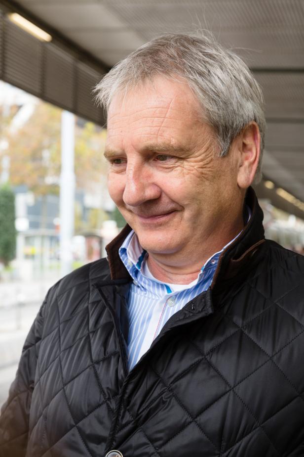 Ein Mann mit grauen Haaren lächelt nachdenklich.