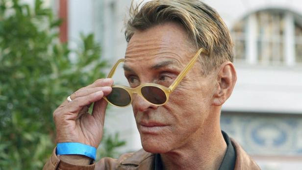 Ein Mann mit Sonnenbrille blickt über den Rand der Gläser.