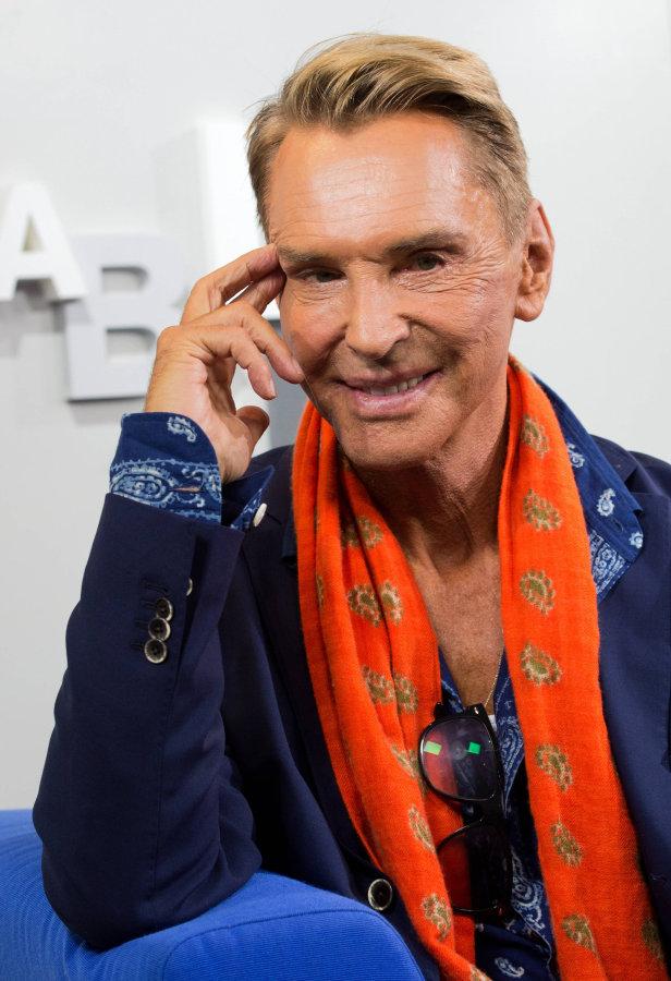 Thomas Gottschalk mit einem orangefarbenen Schal und einem blauen Sakko.
