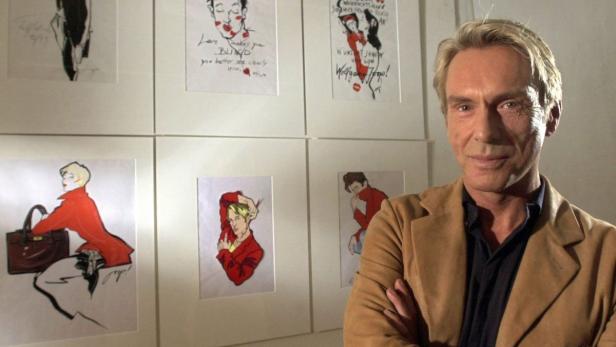 Wolfgang Joop posiert vor einer Wand mit seinen Illustrationen.