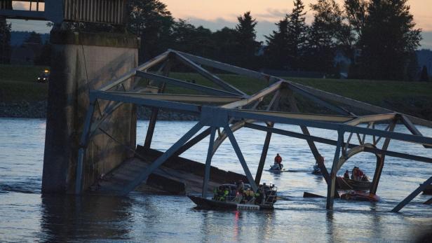 Eine teilweise eingestürzte Brücke über einem Fluss mit Rettungskräften in Booten.