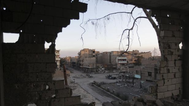 Blick aus einem zerstörten Gebäude auf eine verwüstete Stadt.