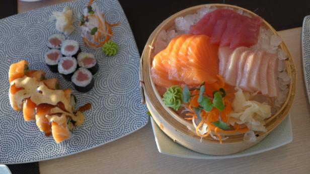 Sushi und Sashimi werden auf Tellern präsentiert.