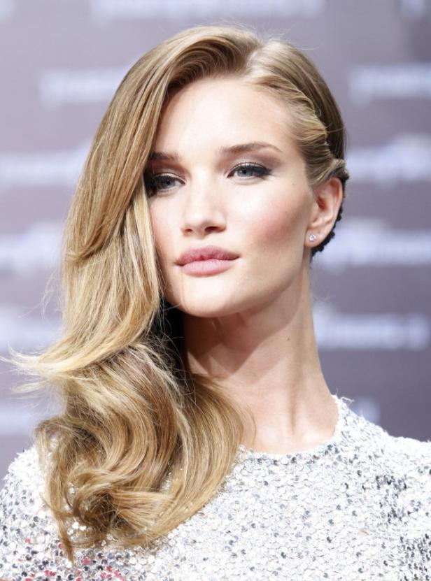 Porträt von Rosie Huntington-Whiteley mit blonden, gewellten Haaren und glitzerndem Kleid.