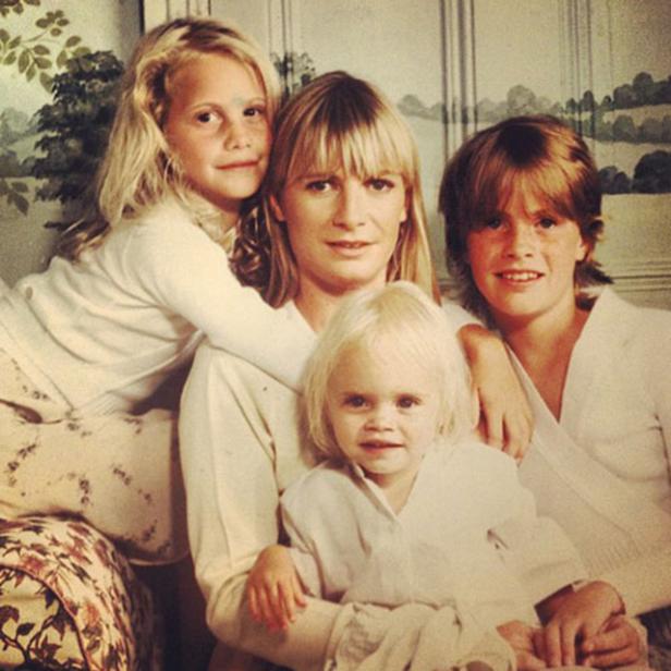 Eine Mutter posiert mit ihren drei Kindern für ein Familienfoto.