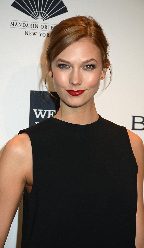 Karlie Kloss lächelt in einem schwarzen Kleid.