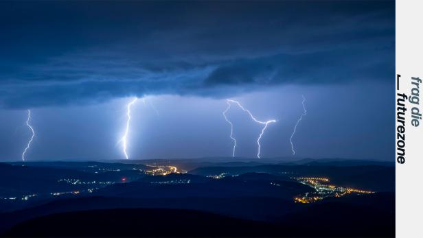 Gewitter in der Nacht über erleuchteten Ortschaften im Gebirge