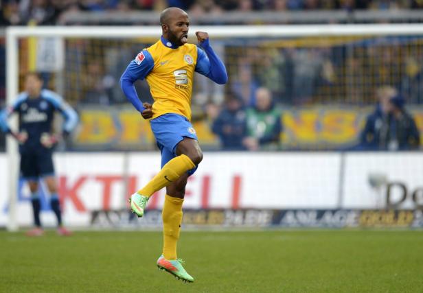 Ein Fußballspieler jubelt auf dem Spielfeld mit herausgestreckter Zunge.