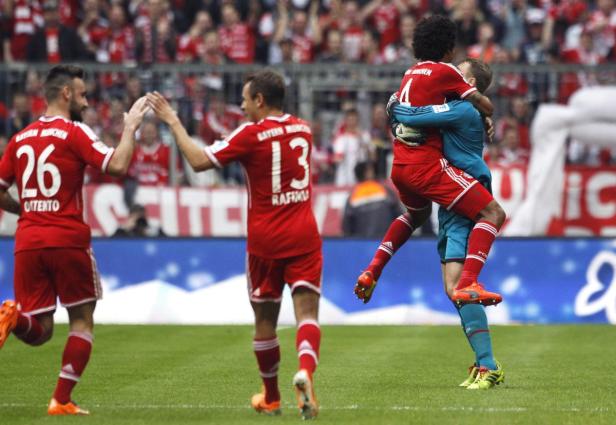 Zwei Fußballspieler des FC Bayern München umarmen sich auf dem Spielfeld.