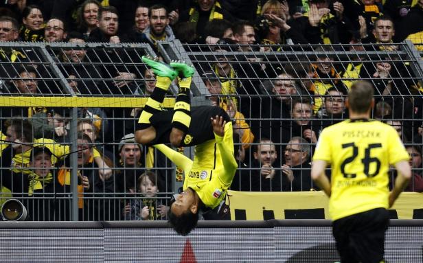 Ein Fußballspieler macht einen Salto vor einer jubelnden Zuschauermenge.