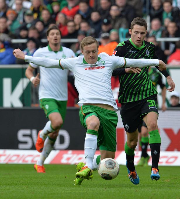 Ein Fußballspieler von Werder Bremen kämpft um den Ball mit einem Spieler von Borussia Mönchengladbach.