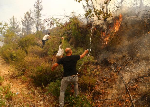 Locals try to extinguish a wildfire near the town of Manavgat